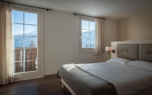 una camera con un letto e due finestre con vista sulle montagne di Hotel Villa Argentina a Cortina dʼAmpezzo