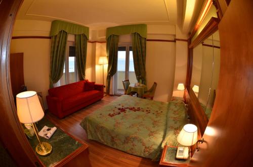 a bedroom with a bed and a red couch at Grand Hotel Montesilvano in Montesilvano