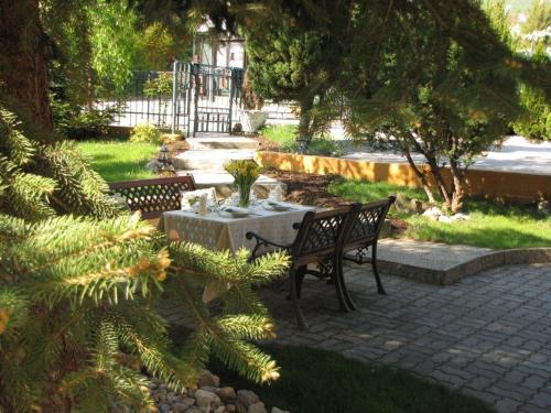 two benches and a table in a garden with trees at Zámok u Grofa in Nitra