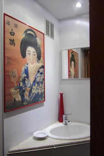 une salle de bains avec une peinture d'une femme sur le mur dans l'établissement Au Gré Du Voyage, à Uzès