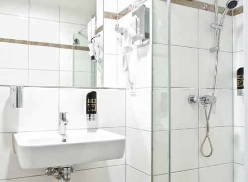 a white bathroom with a sink and a shower at Arena an der Friedberger Warte in Frankfurt/Main