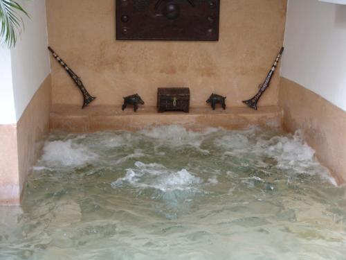 a water feature with four black objects next to a pool of water at Riad Les Nuits de Marrakech in Marrakech