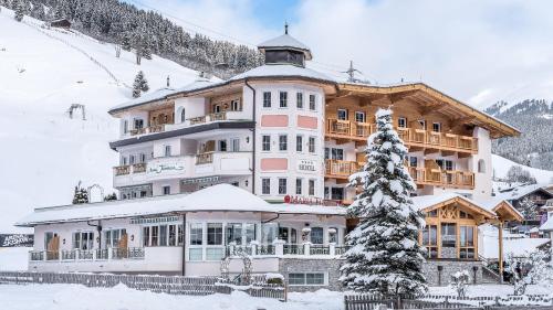 a large building in the snow with a christmas tree at Hotel Maria Theresia in Gerlos