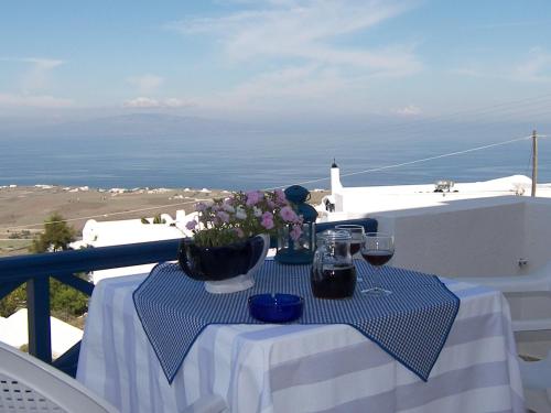 a table with wine glasses and flowers on a balcony at Kiklamino Sunset Studios in Oia