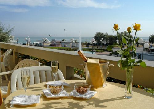 a table with a bottle of wine and flowers on a balcony at Hotel Palace in Senigallia