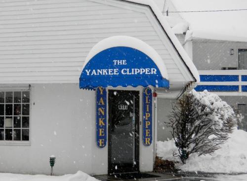 un edificio con un cartel azul y blanco en la nieve en Yankee Clipper Inn en North Conway