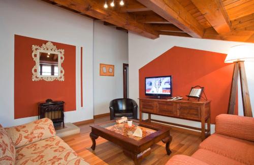 a living room with a couch and a table and a television at La Fonda de Bustio in Bustio