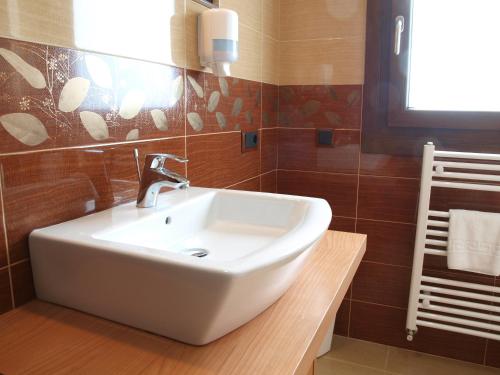 a white sink in a bathroom with brown tiles at Hotel Apartamento Marouco in A Guarda