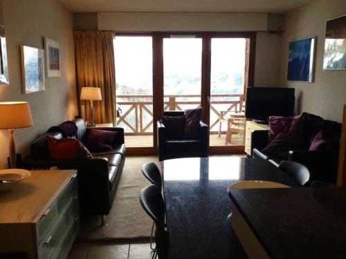 a living room with couches and a table and a balcony at Les Ecureuils Squirrel Lodge in Oz