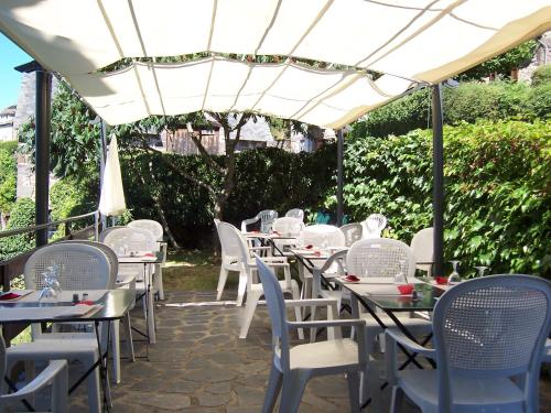 a row of tables and chairs under a white umbrella at Auberge Hôtel de Tournemire - Cantal in Tournemire