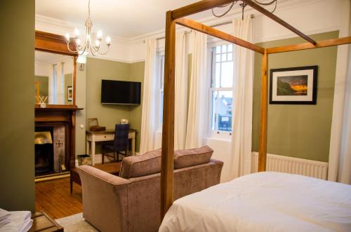 a bedroom with a bed and a chair and a television at The Carrick in Portrush