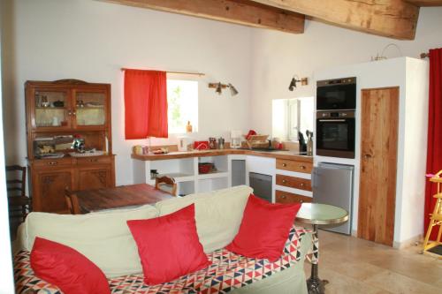 a kitchen with a white couch and red pillows at Mas des Clauzals in Le Cros
