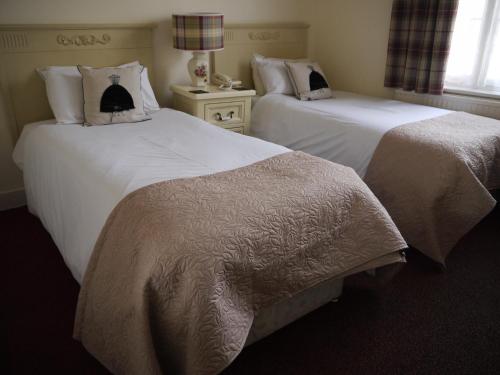 two beds in a hotel room with white sheets at The Bell Hotel in Winslow