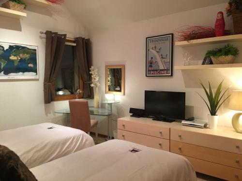 a bedroom with two beds and a desk with a television at Les Ecureuils Squirrel Lodge in Oz