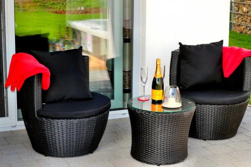 twee stoelen en een tafel met een fles wijn bij Ferienhaus CASA OASIS in Göhren-Lebbin