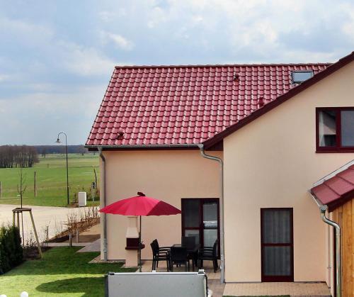 une maison avec un toit rouge et une table avec un parapluie rouge dans l'établissement Ferienhaus CASA PRIMERA, à Göhren-Lebbin