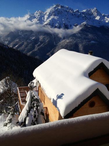 a house covered in snow with mountains in the background at Les Ecureuils Squirrel Lodge in Oz