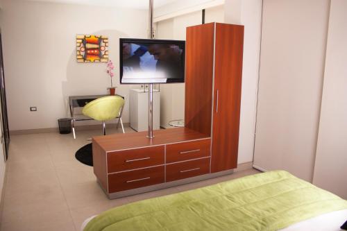 a room with a tv and a wooden cabinet at Sunec Hotel in Chiclayo
