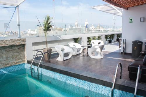 a pool on the roof of a building with white chairs at Sunec Hotel in Chiclayo
