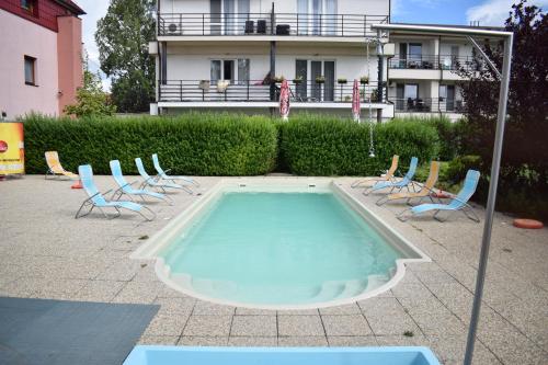 a swimming pool with chairs and a building in the background at Apartmánový Wellness Garni Hotel Relax in Senec