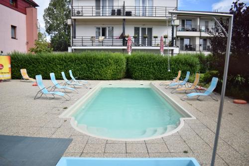 a swimming pool with chairs and a building in the background at Apartmánový Wellness Garni Hotel Relax in Senec