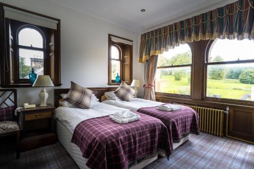 a bedroom with two beds and two windows at Gartmore House Bed & Breakfast in Aberfoyle