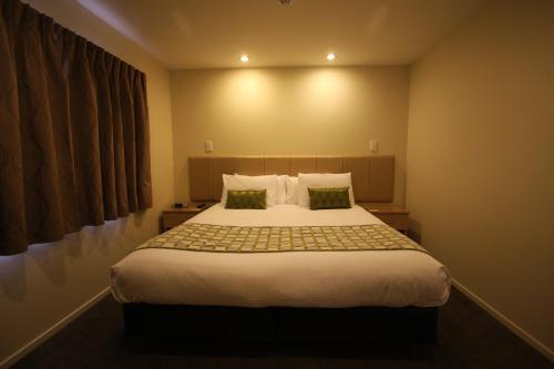 a bedroom with a large bed with white sheets and pillows at 555 Motel Dunedin in Dunedin