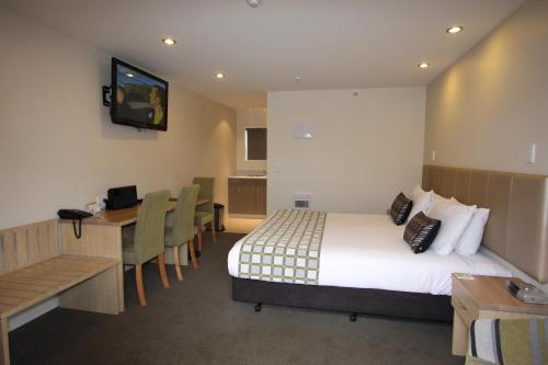 a hotel room with a bed and a desk and a television at 555 Motel Dunedin in Dunedin