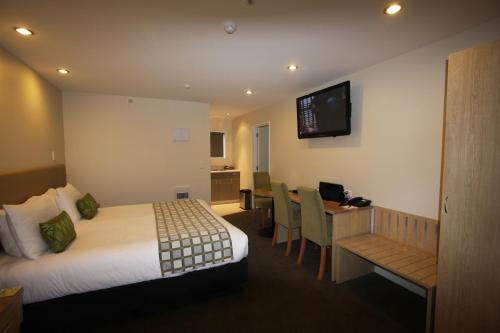 a hotel room with a bed and a table and a desk at 555 Motel Dunedin in Dunedin