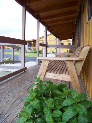 a wooden bench on the porch of a building at Longbourne Lodge Motel Mosgiel in Mosgiel