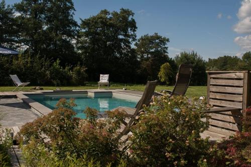 basen z dwoma krzesłami ogrodowymi obok niego w obiekcie Le Duplex de la Raveline w mieście Sart-lez-Spa