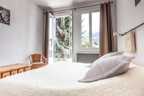 a bedroom with a large white bed and a window at La Grande Eperviere in Barcelonnette