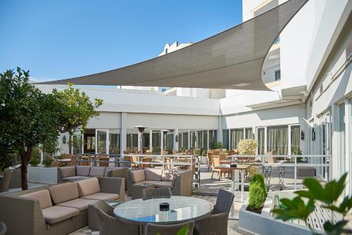 a patio with couches and tables and chairs at Dona Filipa Hotel in Vale do Lobo