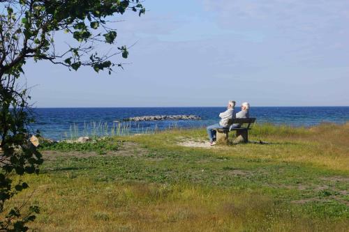 two people sitting on a bench looking at the ocean at Ystad Camping in Ystad