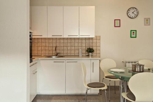 une cuisine avec des placards blancs et une table avec des chaises dans l'établissement Zagi Apartment, à Zagreb