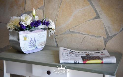 a vase of flowers sitting on a table with a newspaper at RE UMBERTO b&b - Suite di charme e Country rooms in San Salvo