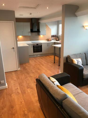 een woonkamer met een bank en een keuken bij Apartment 5, Cornerhouse Apartments in Llandudno