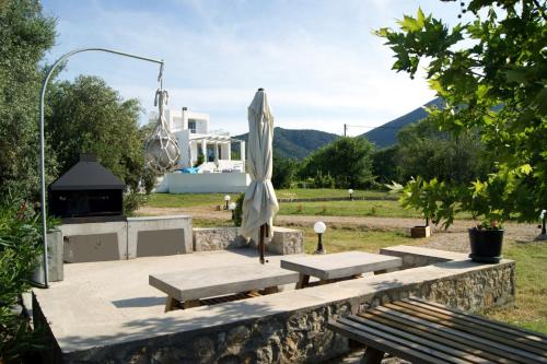 a patio with benches and an umbrella and a grill at Manna Gea in Vonitsa