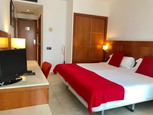a bedroom with a large bed with a red blanket at Hotel Calasanz in Molins de Rei