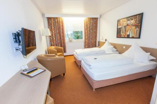 um quarto de hotel com duas camas e uma secretária em Hotel am Springhorstsee em Grossburgwedel