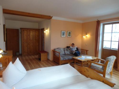 a person sitting on a couch in a room at Landhaus Lenzenhof in Reit im Winkl