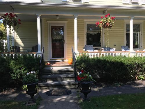 a house with a porch with potted plants on it at Cooperstown Bed and Breakfast in Cooperstown