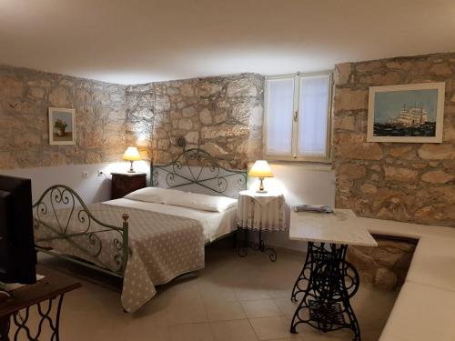 - une chambre avec un lit et un mur en pierre dans l'établissement Apartments Gabri, à Mali Lošinj