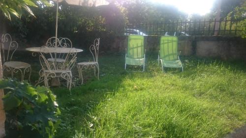 three chairs and a table in a yard at Le vieux Pressoir in Saint-Germain-lès-Arlay