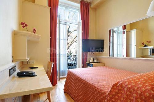 a bedroom with a bed and a desk and a window at Rhodes Hotel in London