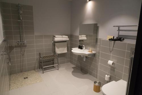 a bathroom with a sink and a shower at The Originals Boutique, Hôtel des Sources, Nevers Nord in Pougues-les-Eaux