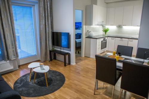 a living room with a kitchen and a table with chairs at Antintorni Apartment 2 in Pori