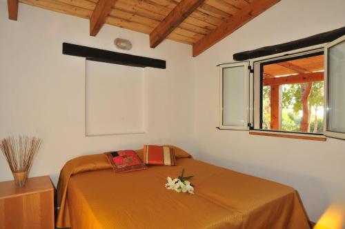 a bedroom with a bed with orange sheets and a window at Villaggio Camping Torre Del Porticciolo in Porto Conte