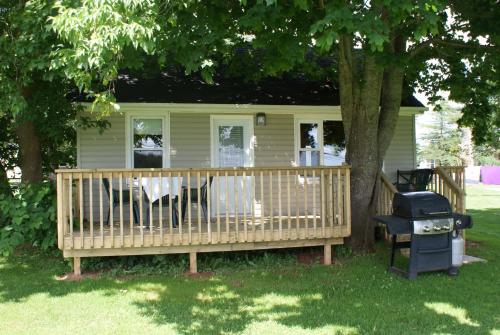 a house with a porch with a chair and a grill at North Rustico Motel & Cottages in North Rustico