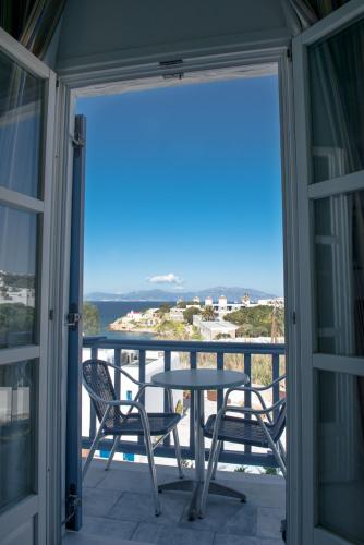 a balcony with a table and chairs and a view of the ocean at Poseidon Hotel Suites in Mýkonos City